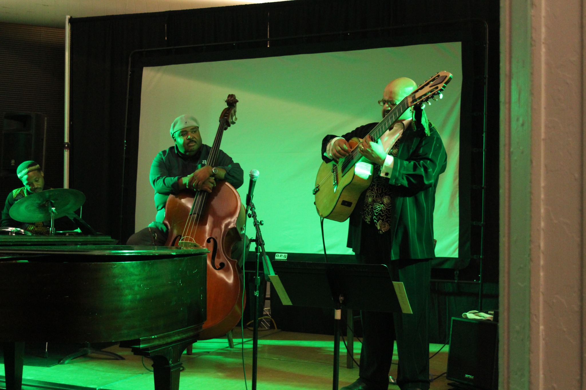 Jazz musicians performing on drums, upright bass, and guitar during the anniversary event